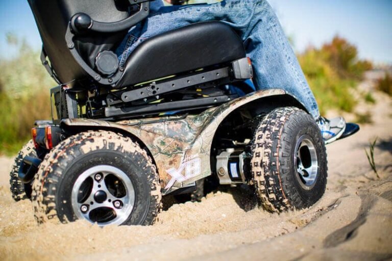 A rugged all-terrain wheelchair parked on a wooden path surrounded by nature.